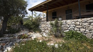 A stone-walled building with a wooden roof and a stone staircase leading up to it. - Anemos Studio (Zakynthos)