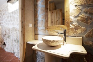 A stone wall bathroom with a stone sink and a wooden door.