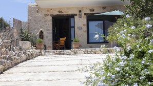 A stone building with a doorway, a window, and a chair outside. - Anemos Studio (Zakynthos)