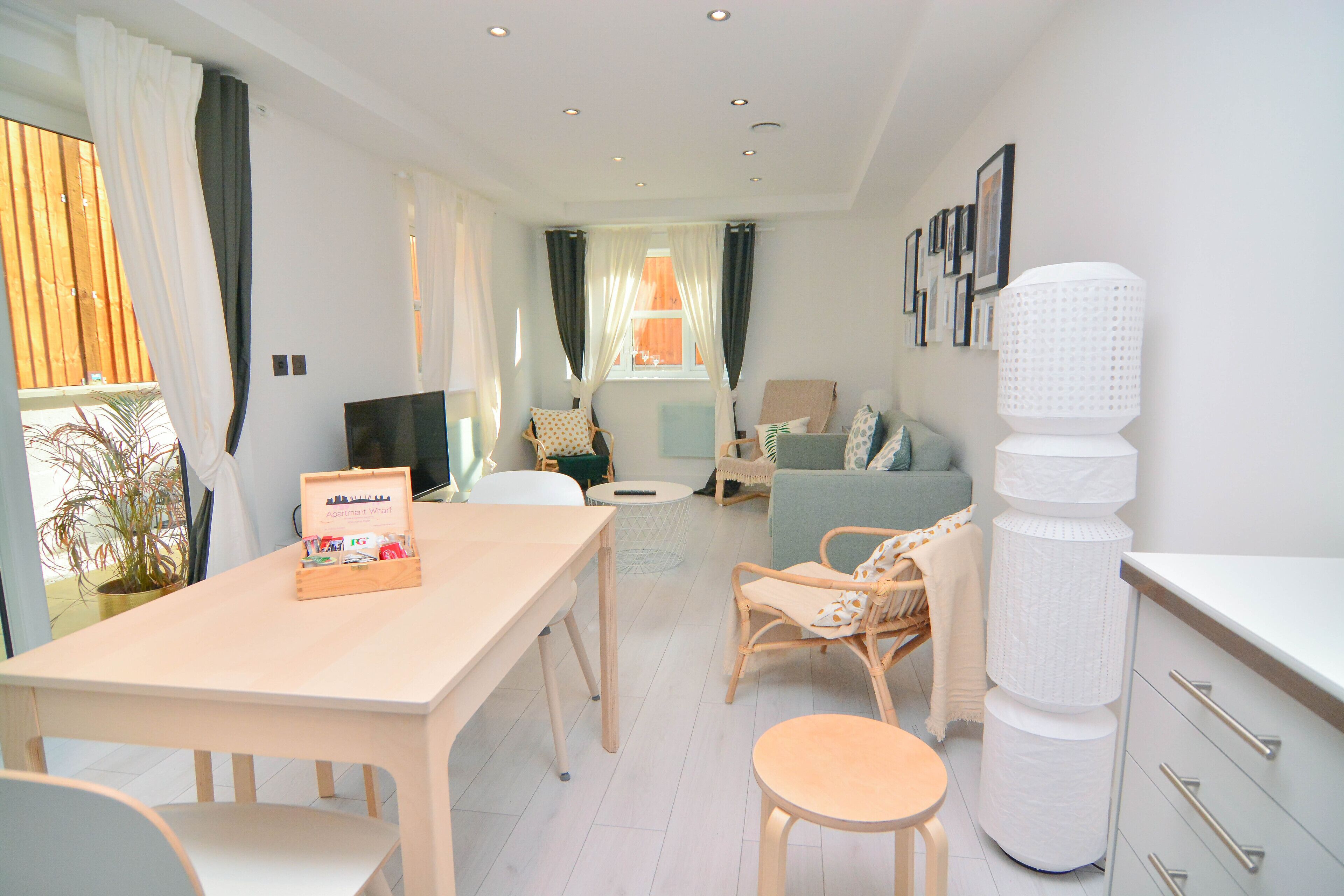 Un salon moderne comprenant un coin repas, un canapé, un téléviseur et un grand élément décoratif blanc.