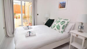 Ett hotellrum med en säng, ett nattduksbord, en lampa och utsikt över omgivningarna.