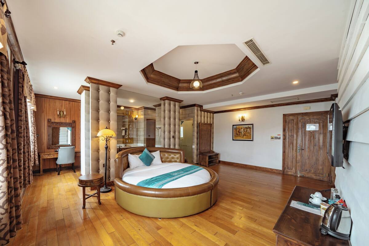 A spacious bedroom with a large round bed, a desk, and a wardrobe.