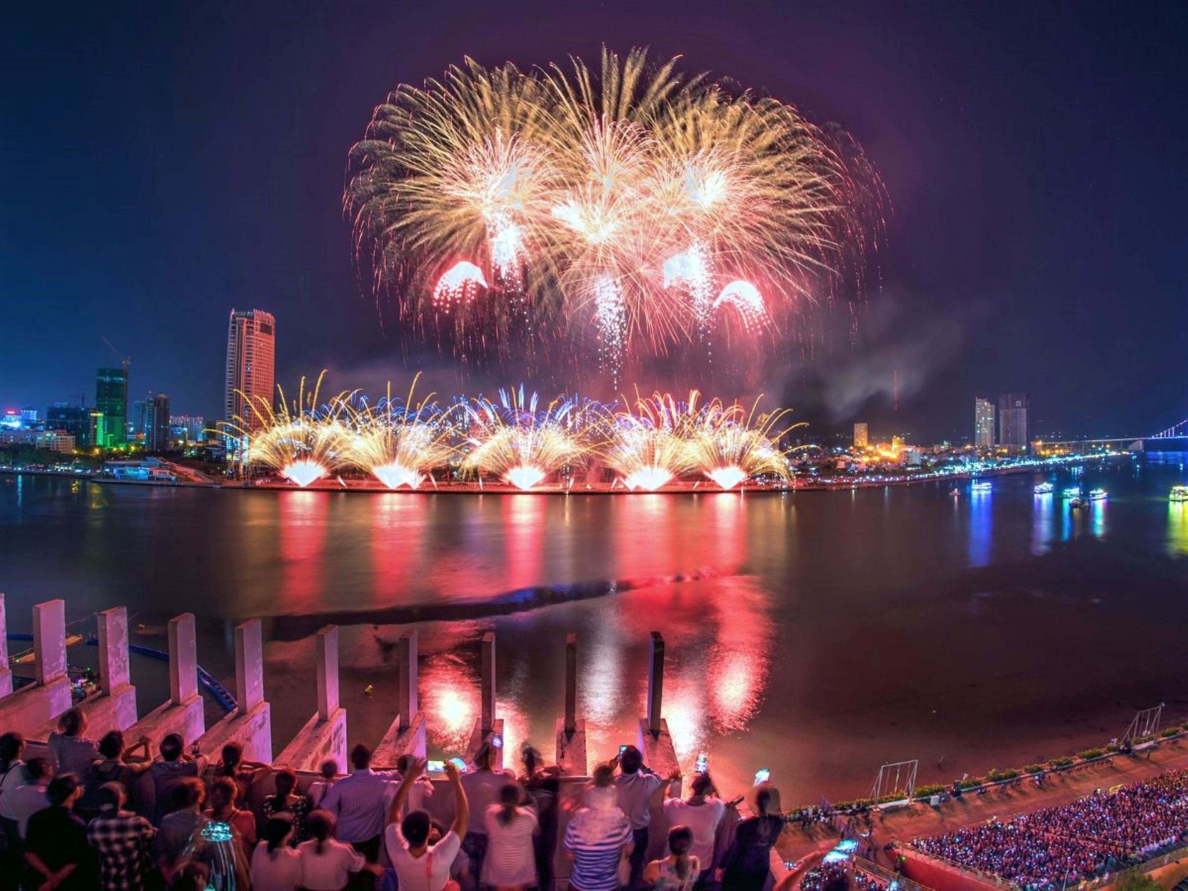 A waterfront cityscape with fireworks display over the water.