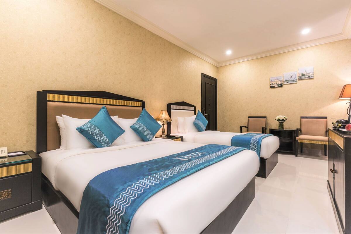 A hotel room with two beds, a desk, and a chair.