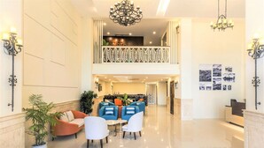 A spacious lobby with a high ceiling, a balcony with decorative railings, and a reception desk. - IBIZA Riverfront Da Nang Hotel (Da Nang)