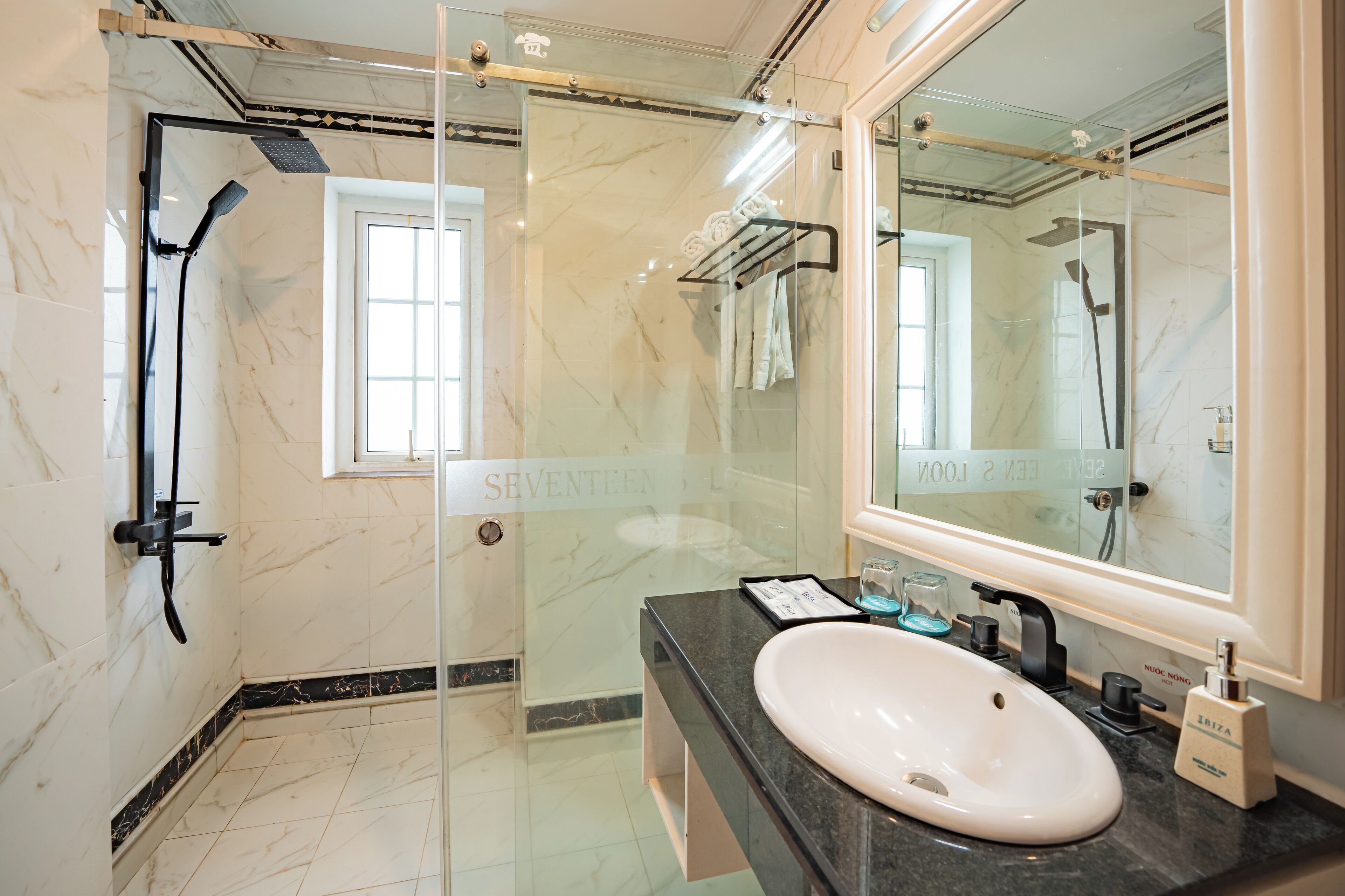 Une salle de bain moderne avec une douche à parois de verre, un lavabo blanc et un grand miroir.