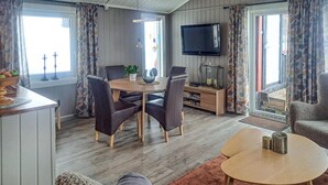 Un salon chaleureux avec une table à manger en bois, deux chaises, un téléviseur et une cheminée.