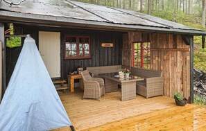 A rustic wooden cabin with a covered deck, wicker furniture, and a sign reading "Gleden".