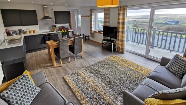 Un appartement moderne comprenant une cuisine, un coin repas, un salon et un balcon avec vue.