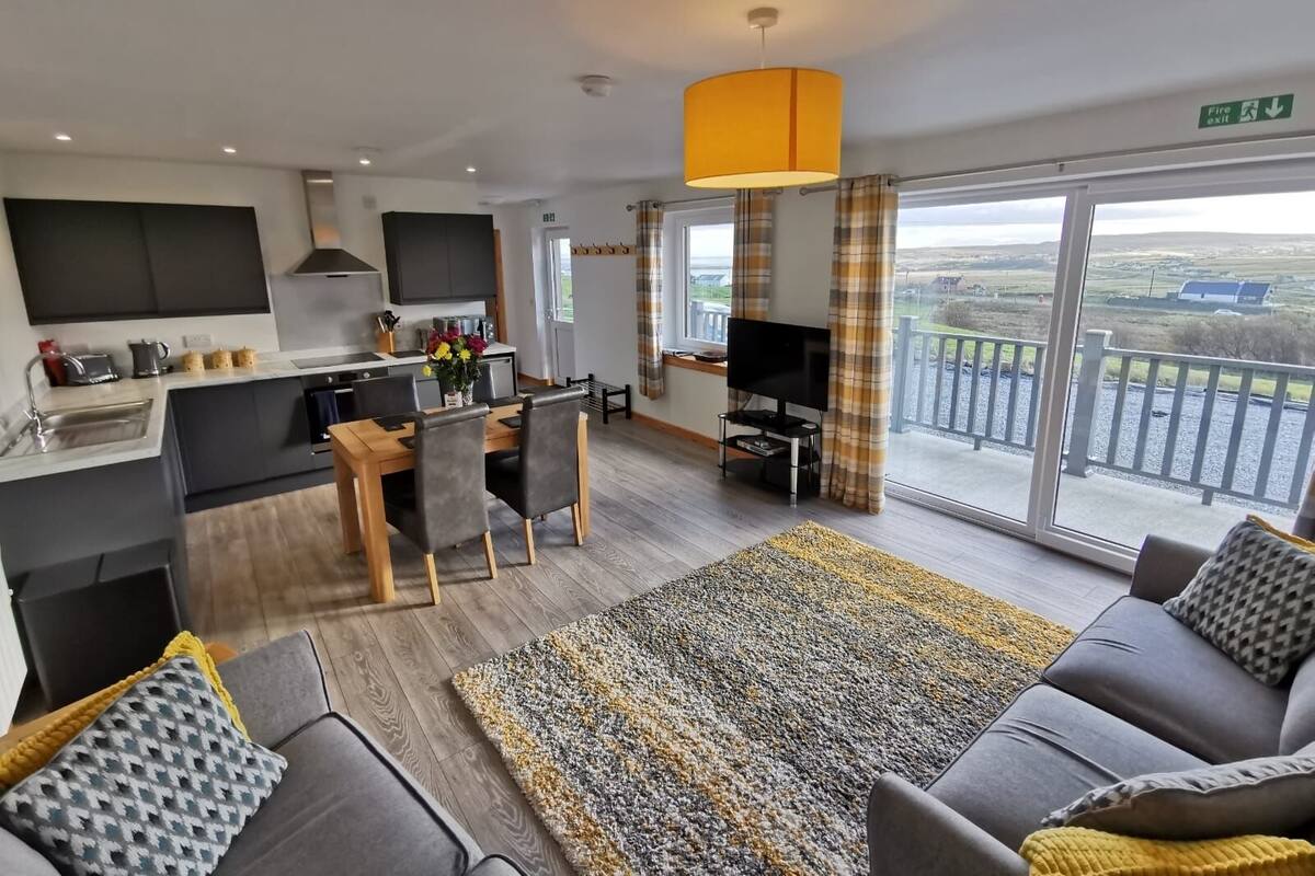 A modern apartment with a kitchen, dining area, living room, and a balcony with a view.