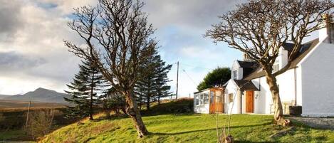 Un bâtiment blanc avec un toit en pente, une petite construction attenante et un ciel dégagé.