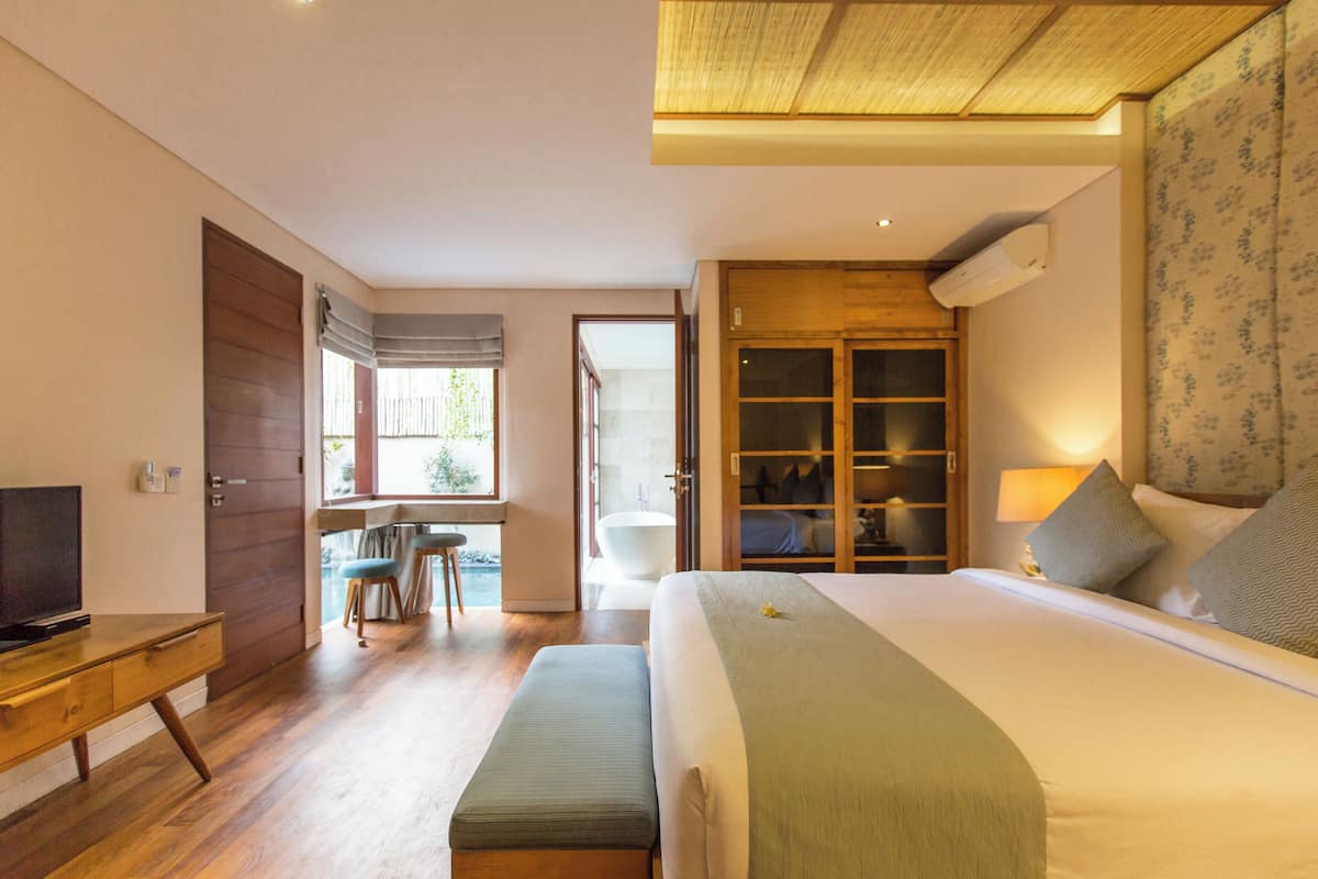 A bedroom with a bed, a desk, a chair, a bathroom, and a closet.