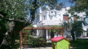 A green playhouse with a red roof, surrounded by trees and a white building in the background. - B&B dal Barbarossa (Vasto)