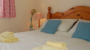 A neatly made bed with blue and white pillows, a wooden headboard, and folded towels on the bed.