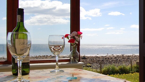 A table with a wine bottle, two wine glasses, a vase with flowers, and a book titled "Country Living" by countryliving.co.uk.