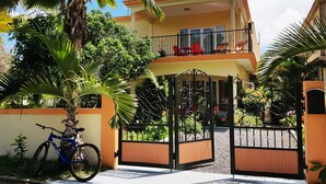 Une maison à deux étages avec un balcon, un portail et un vélo garé devant.