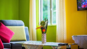 Une pièce avec un canapé, une petite table sur laquelle se trouve un vase, et une fenêtre avec des rideaux.