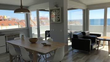 Eine moderne Wohnung mit Essbereich, Wohnraum mit Sofa und Tisch, und großen Fenstern mit Blick auf die Stadtlandschaft.