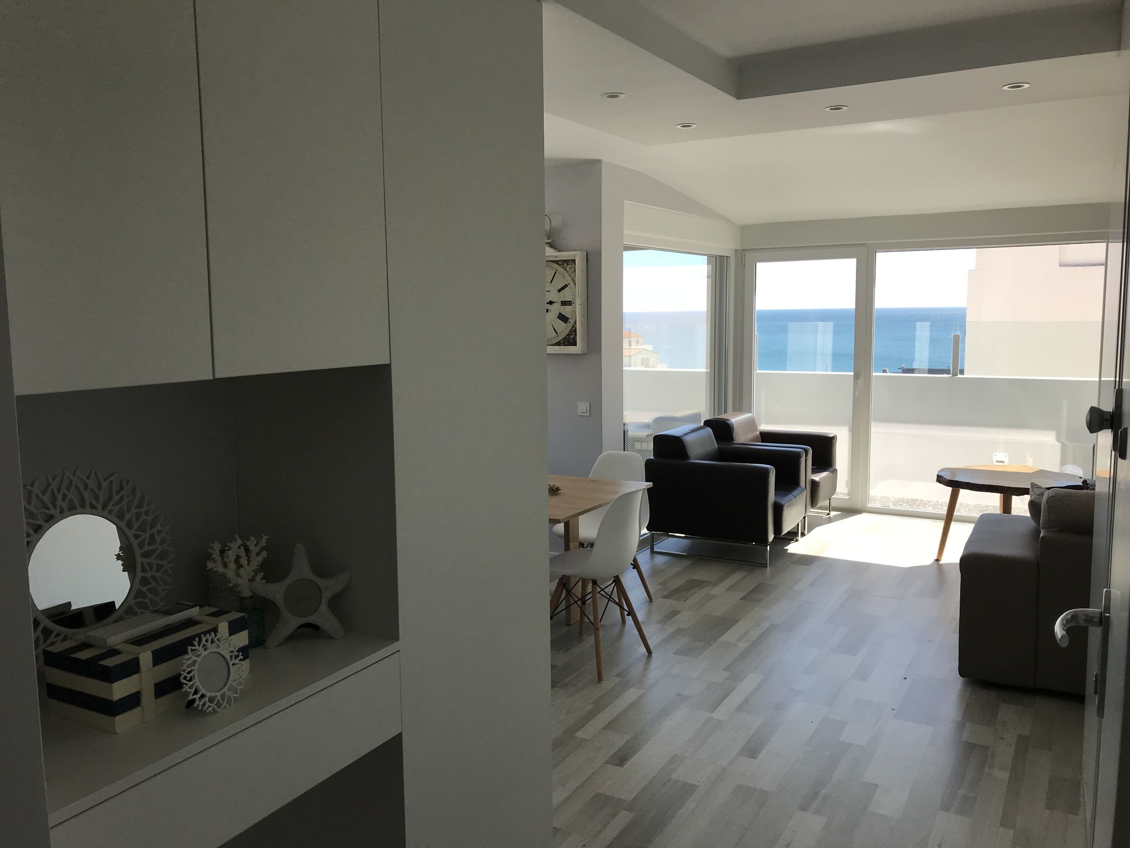 Ein modernes Wohnzimmer mit Balkon, Essbereich und Meerblick.