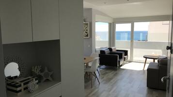 Ein modernes Wohnzimmer mit Balkon, Essbereich und Meerblick.