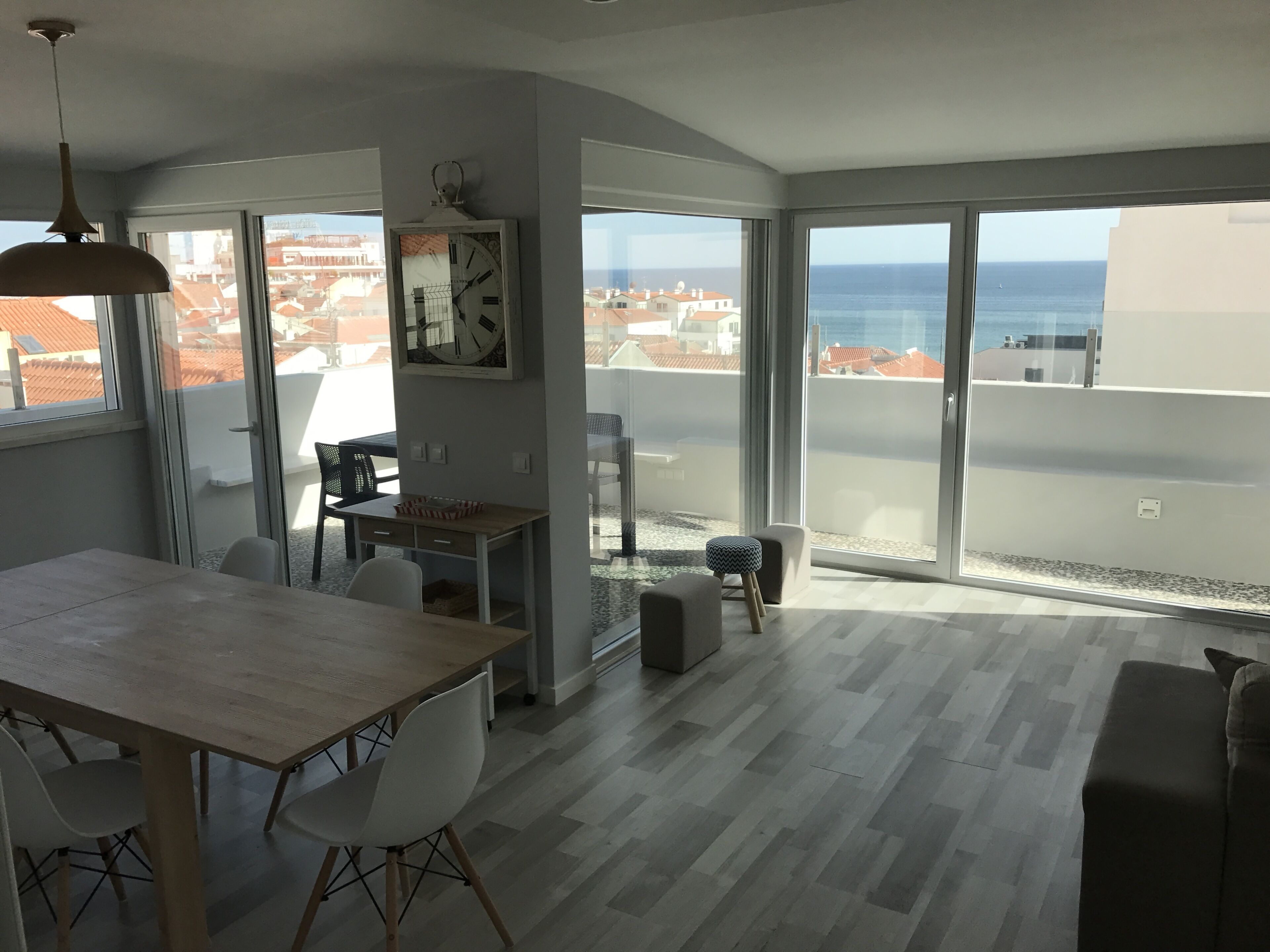 Een moderne woonkamer met een eethoek, grote schuifdeuren en uitzicht op zee.