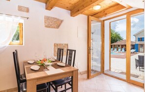 A dining area with a wooden table, chairs, and a glass door leading to an outdoor pool area. - Pet friendly home in Bibici with sauna (Bibici)