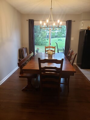 Enjoy meals in this dining area with a large table and comfortable chairs, surrounded by a beautiful garden view.