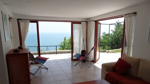 A living room with a sofa, a coffee table, and two chairs. There is a view of the sea through large windows. - Beautiful villa, stunning views, great location (Kranevo)