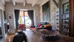 Ein geräumiger Wohnbereich mit einem Holzessttisch, einer Couch mit Kissen, einem Sessel und einer an der Wand stehenden Leiter.