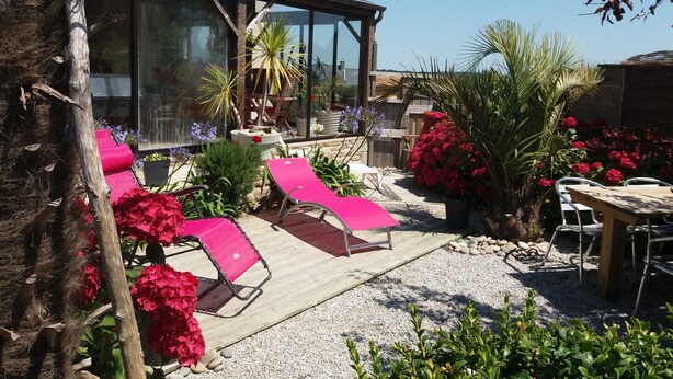 Eine Terrasse mit Liegestühlen, einer Holzterrasse und Topfpflanzen.