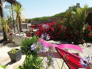 A garden with potted plants, a red chair, and a wooden deck.
