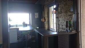 Eine kleine Küche mit Steinwand, Fenster und Barbereich mit Flaschen.