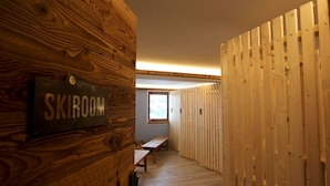 A hallway with wooden walls, a bench, and a sign labeled "SKIROOM". - High-quality apartment with a private sauna and a dream view right on the ski slope (Westendorf)