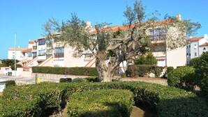 A residential area with a large tree in the foreground, surrounded by well-maintained hedges. - Saint-Cyprien Rental: 2-room apartment with parking, terraces, and loggia (Saint-Cyprien)