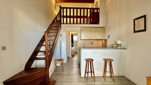 A staircase leading to a second floor, a kitchen with a bar area, and a framed certificate on the wall. - Saint-Cyprien Rental: 2-room apartment with parking, terraces, and loggia (Saint-Cyprien)