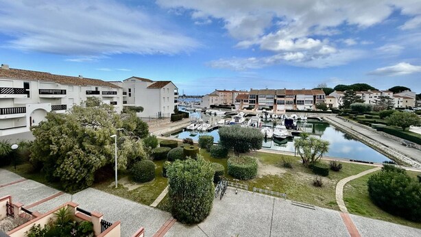 A marina with boats, a clear sky, and residential buildings with balconies. - Saint-Cyprien Rental: 2-room apartment with parking, terraces, and loggia (Saint-Cyprien)