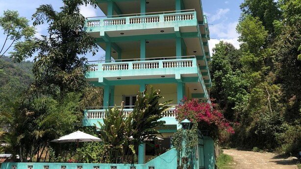 A multi-story building with balconies, labeled as a guesthouse and restaurant, surrounded by greenery. - Happy Sedi Lodge (Pokhara)