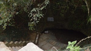 A stone staircase leading into a tunnel with a sign warning of a steep incline. - Happy Sedi Lodge (Pokhara)