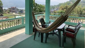A balcony with a hammock, chairs, and a table. - Happy Sedi Lodge (Pokhara)