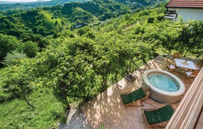 Una terraza en la azotea con un jacuzzi, dos sillones de descanso y vistas a un paisaje verde exuberante.