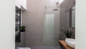 A modern bathroom with a glass shower enclosure, a white sink, and a small potted plant. - Kalsa miniLoft by Wonderful Italy (Palermo)