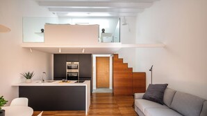 A modern apartment with a kitchen, dining area, and a living room with a sofa and a staircase leading to an upper level. - Kalsa miniLoft by Wonderful Italy (Palermo)