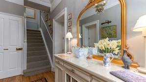 A staircase with a patterned carpet, a white door, and a mirror with a gold frame. - Puddle Duck Lodge (Windermere)