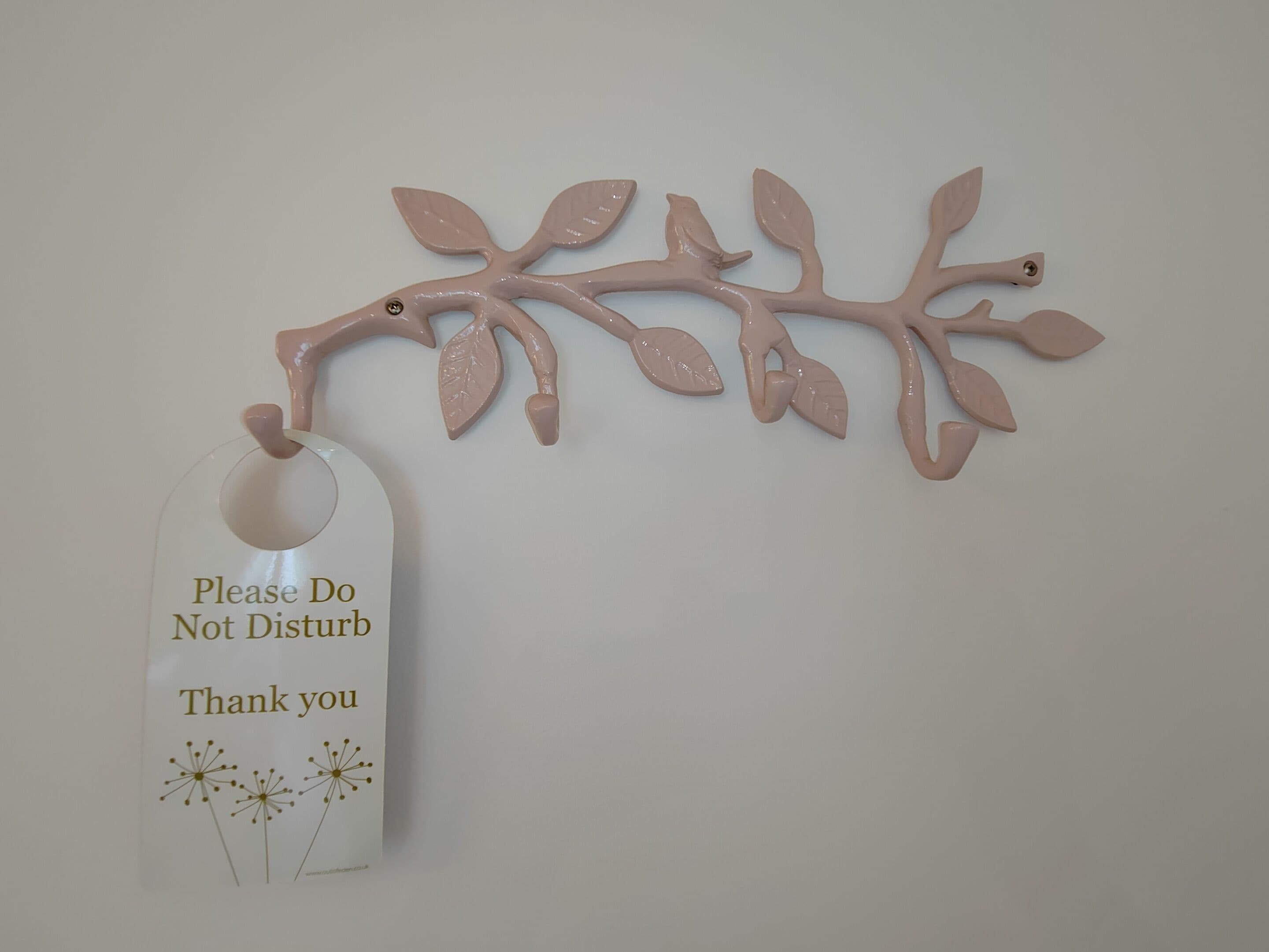 A wall-mounted branch decoration with a tag that reads "Please Do Not Disturb Thank you".