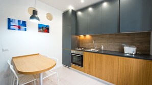 Una cocina moderna con una mesa y sillas de madera, horno empotrado y tostadora.