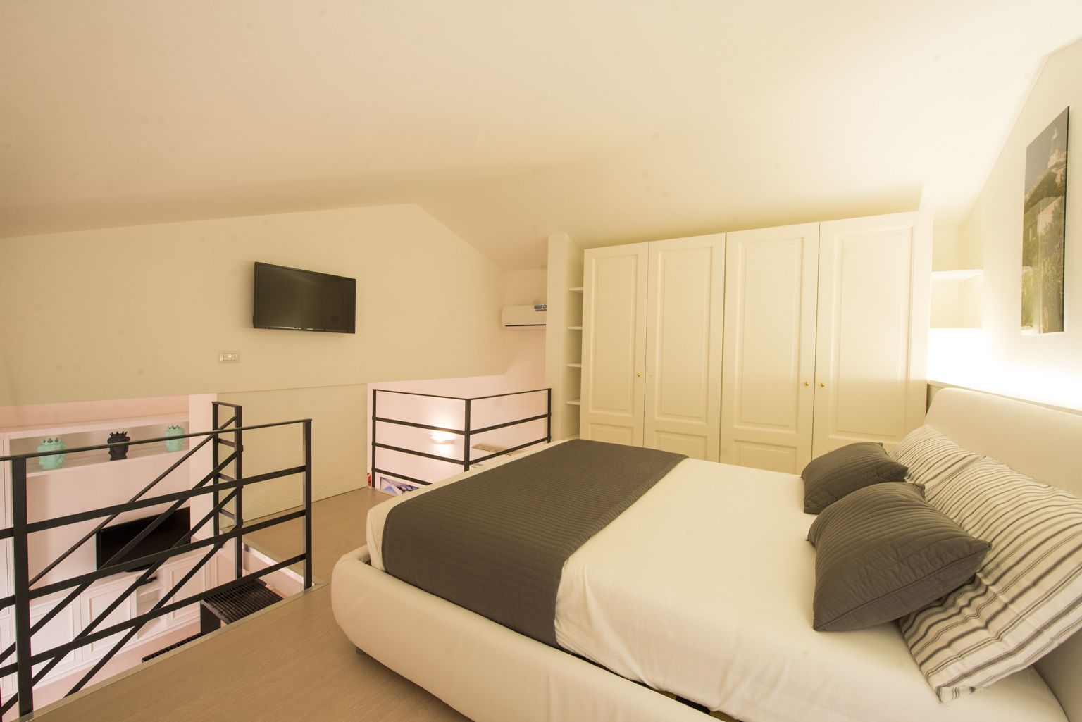 A bedroom with a bed, a desk, a TV, and a wardrobe.