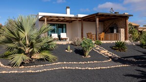A modern house with a stone exterior, a wooden pergola, and a patio with chairs and a table. - cozy finca to relax and be active (Triquivijate)