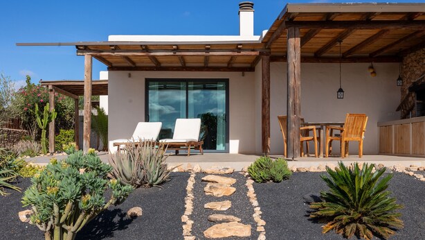 A modern house with a patio area featuring a stone pathway, outdoor furniture, and various desert plants. - cozy finca to relax and be active (Triquivijate)