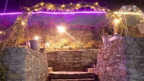 A stone staircase leading up to a platform with a decorative arch and string lights. - Blossom Bliss Resort (Dhari)