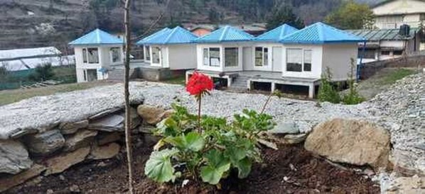 Filas de casas con techos azules y paredes blancas, rodeadas por un paisaje rocoso.
